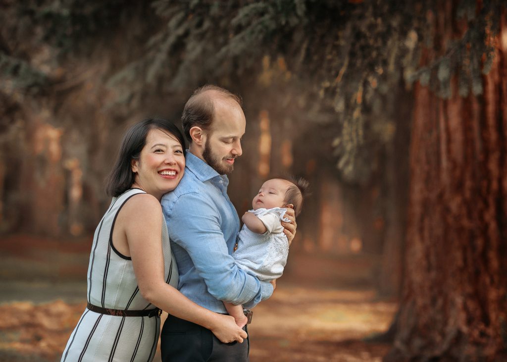 mum dad and baby posing in natural way in Cheam park hugging smiling Morden Surrey photoshoot