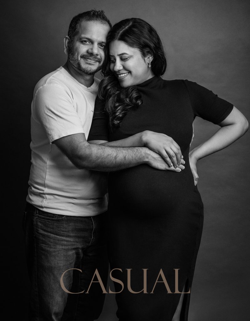 casual black and white pregnancy couple studio photoshoot a couple standing hugging the belly together smiling wearing casual clothes natural emotion maternity photoshoot in Sutton Surrey and London