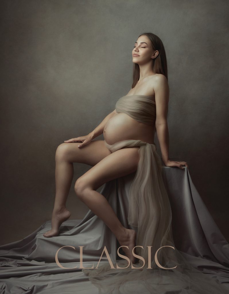 Classic fine art maternity studio portrait painterly mood pregnant lady sitting covered in soft fabric open belly and dreamy mood Sutton London Surrey professional pregnancy photoshoot