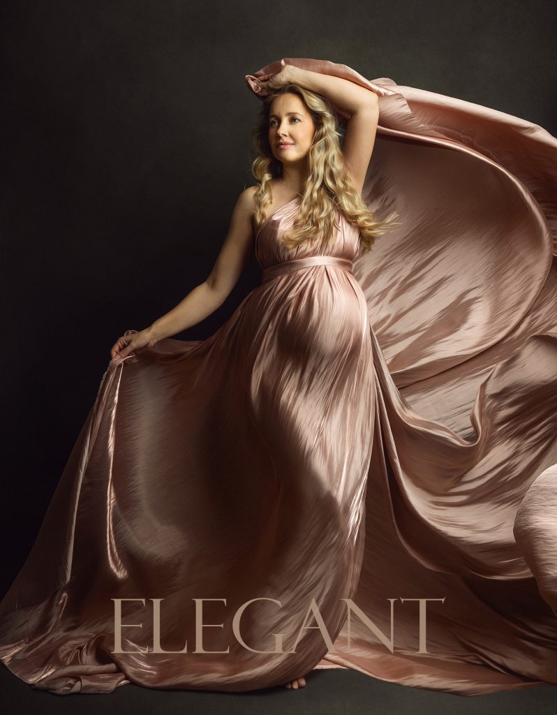 Elegant maternity studio portrait pregnant lady standing wrapped in a flowing silk rosy fabric motion and feminine pose pregnancy photoshoot in Sutton London and Surrey