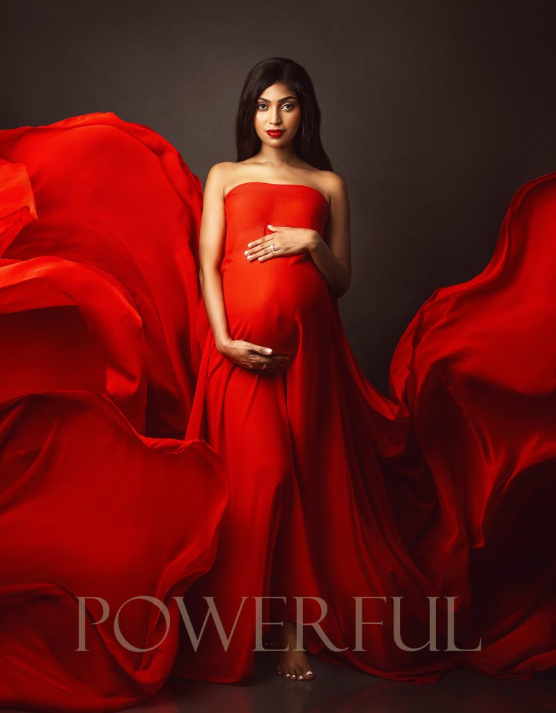 red bold powerful professional studio maternity portrait pregnant lady holding red flowing fabric strong pose holding belly maternity photographer in Sutton Surrey and South London
