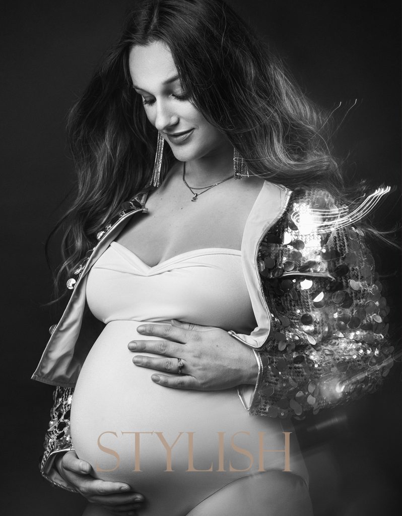 fashion stylish studio maternity portrait pregnant lady holding a belly looking down black and white photo maternity photoshoot in Sutton Surrey and South London