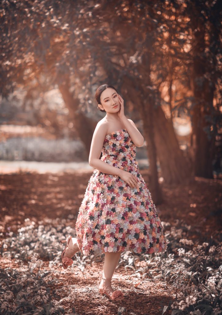personal creative portrait young lady wearing floral summer dress smiling at the camera surrounded by Beddington Park trees, Wallington photoshoot