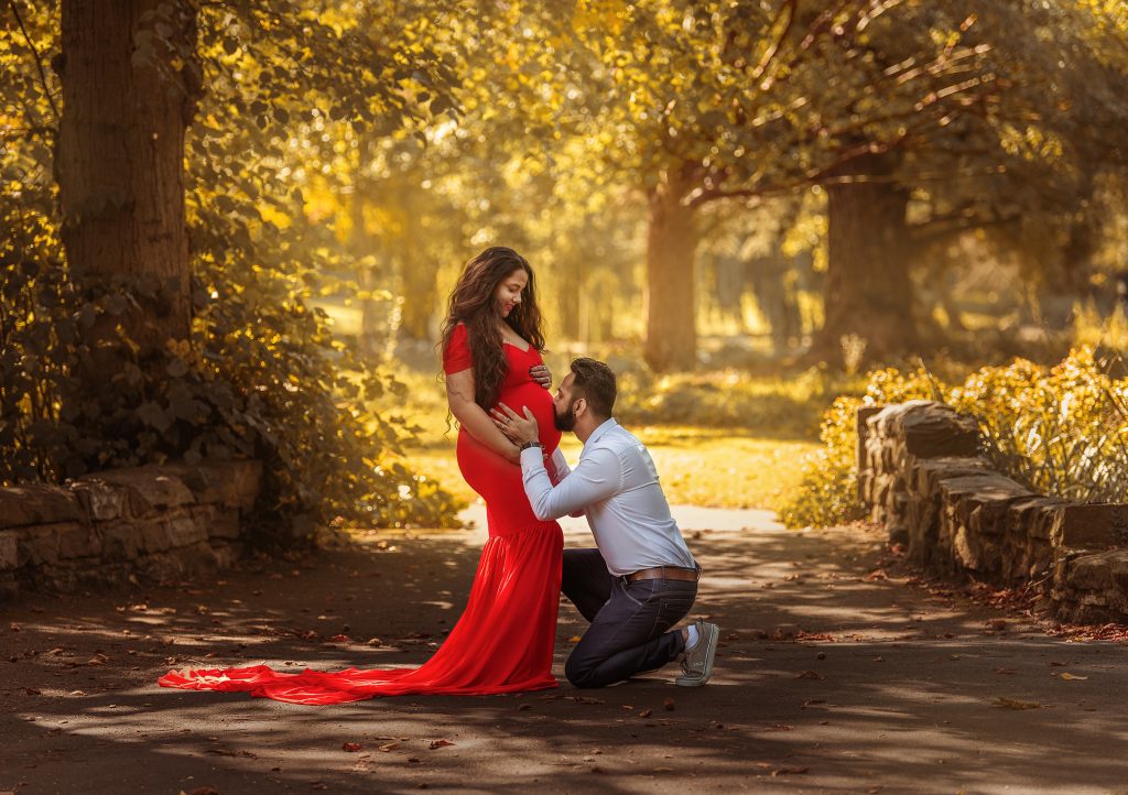 maternity family photoshoot at Beddington Park Wallington couple husband holdding kissing belly happy moment pregnancy long red dress Sutton South London photographer