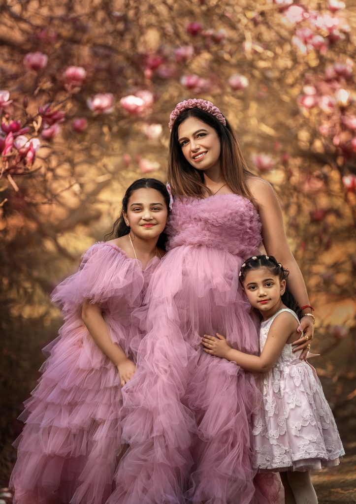 maternity and children family photo at blooming park wearing pink ruffled dresses smiling hugging happy romantic mood Surrey maternity photoshoot