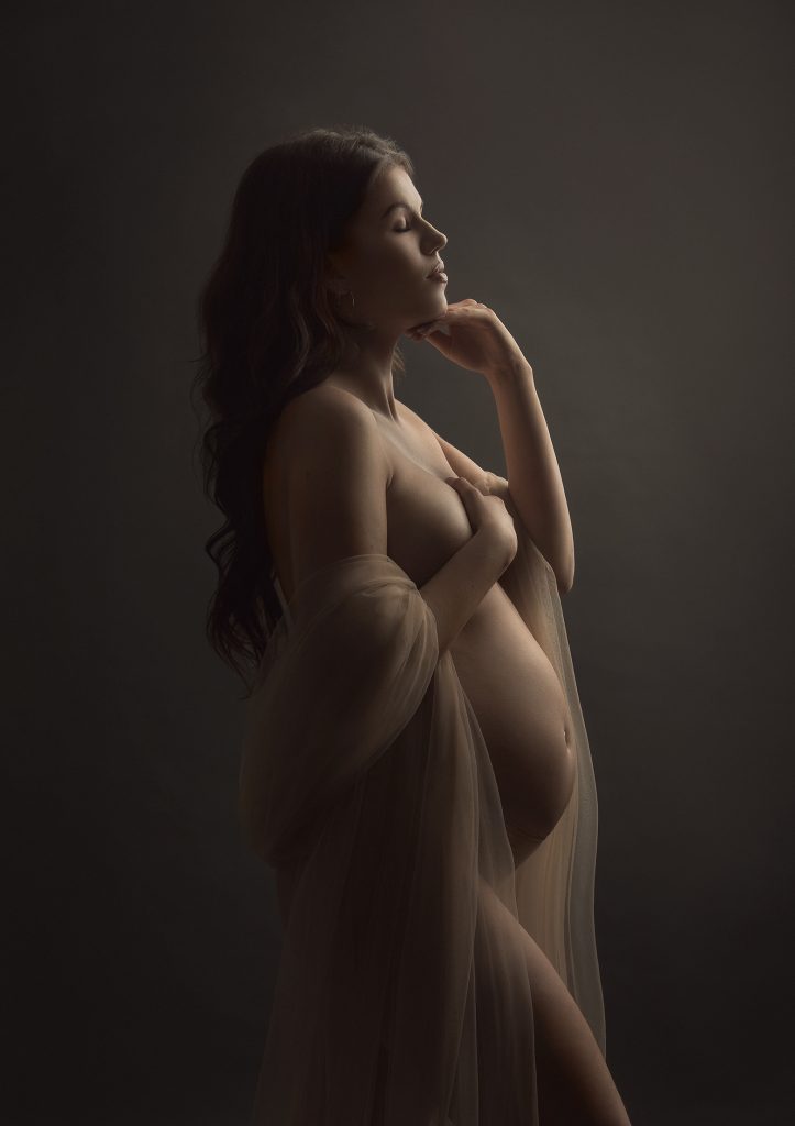 dreamy soft light studio pregnancy portrait lady standing on the side in a natural pose semi nude pregnancy professional portrait in Sutton Surrey