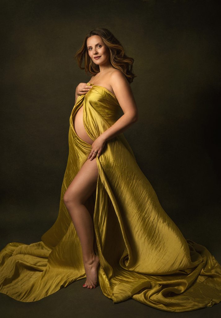 Elegant maternity studio dreamy pose lady smiling holding belly holding satin flowing fabric classic Surrey South London photography