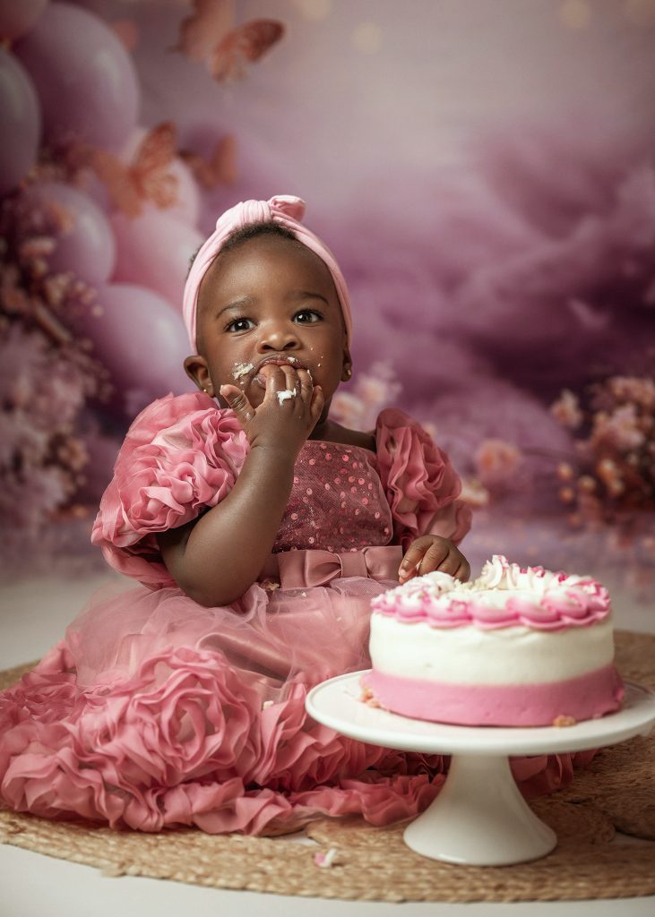 baby girl studio cake smash first birthday photo pink dress black skin baby girl floral backdrop Sutton Surrey South London photoshoot