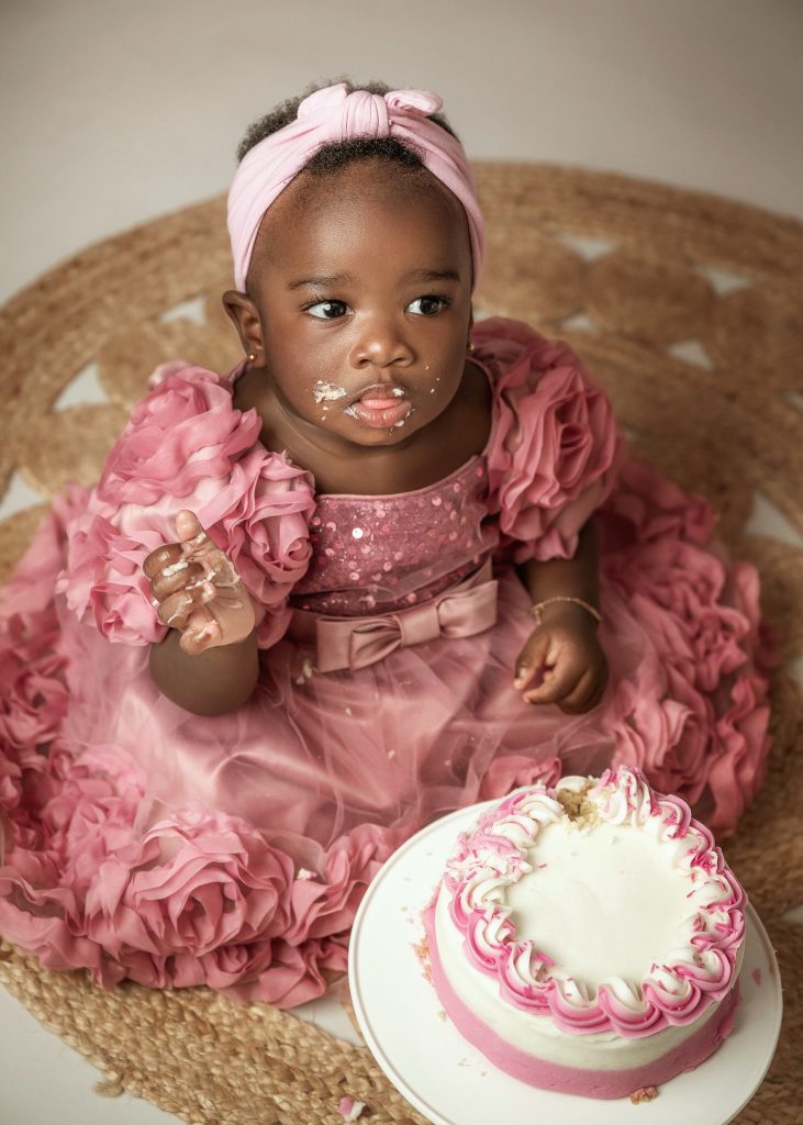 baby girl studio cake smash first birthday photo pink dress black skin baby girl floral backdrop Surrey South London
