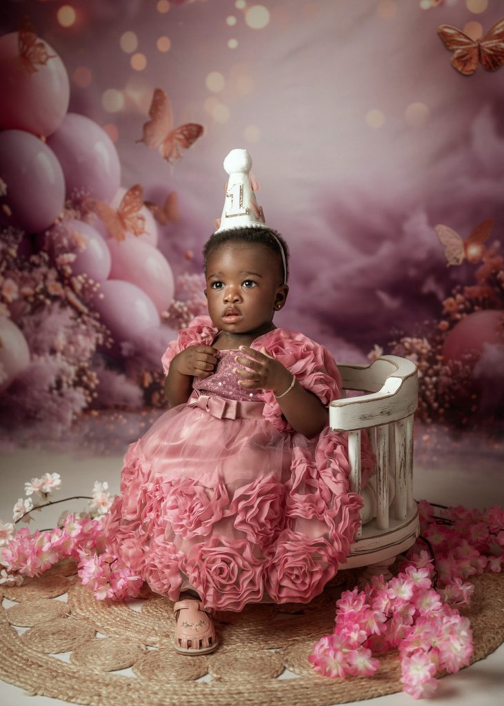baby sitting in a baby posing chair first baby girl's studio painterly style pink dress and butterflies theme photoshoot in South London
