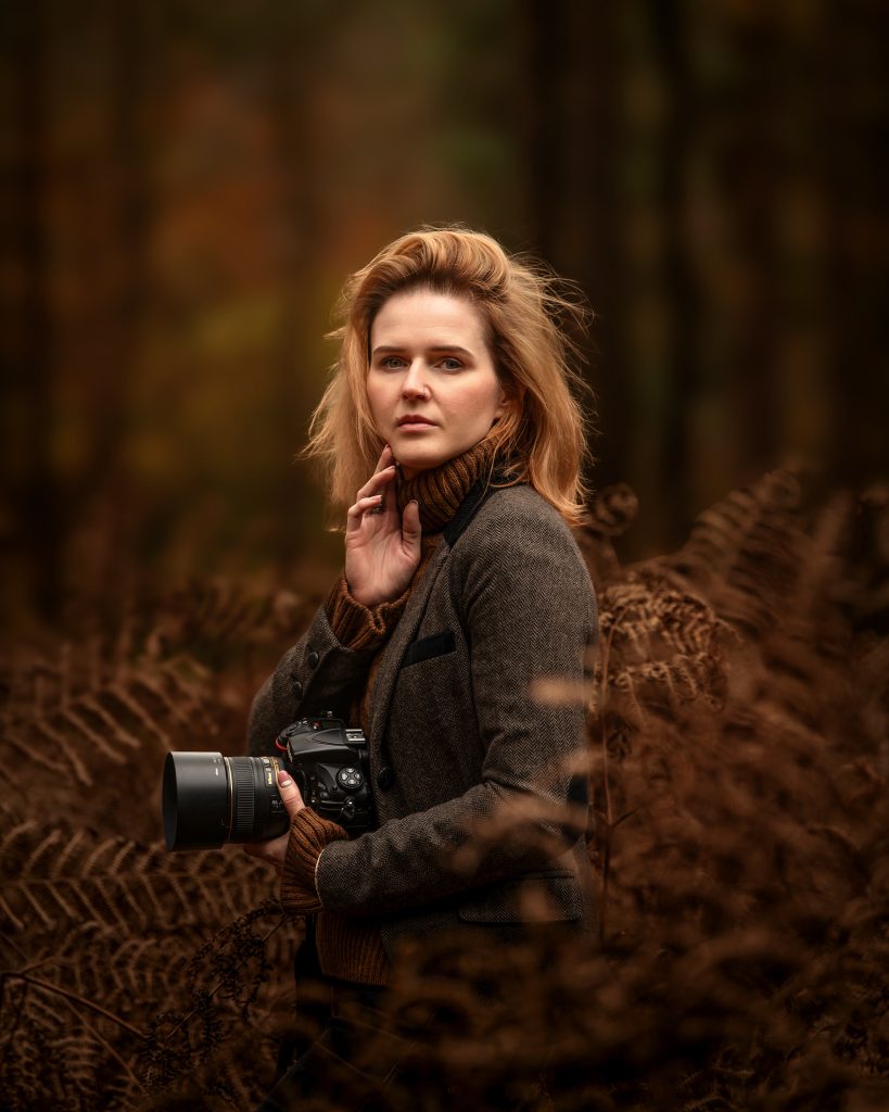 personal portrait as a photographer in Surrey woods holding my camera gear earthy colours natural pose Sutton, Surrey photographer