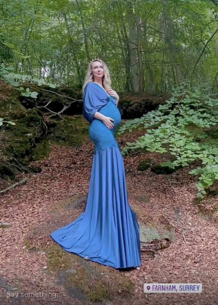 pregnancy photoshoot back stage in the Surrey woods lady wearing long blue royal style dress and posing naturally stress free