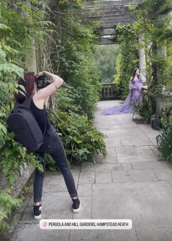 Award-winning maternity photographer gently guiding pregnant woman during photoshoot in London park behind the scenes screenshot