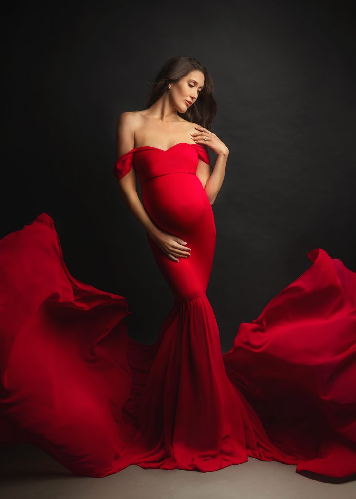 Award-winning maternity photographer in Surrey creating elegant pregnancy portraits studio pregnancy photo lady wearing long red dress editorial classic style
