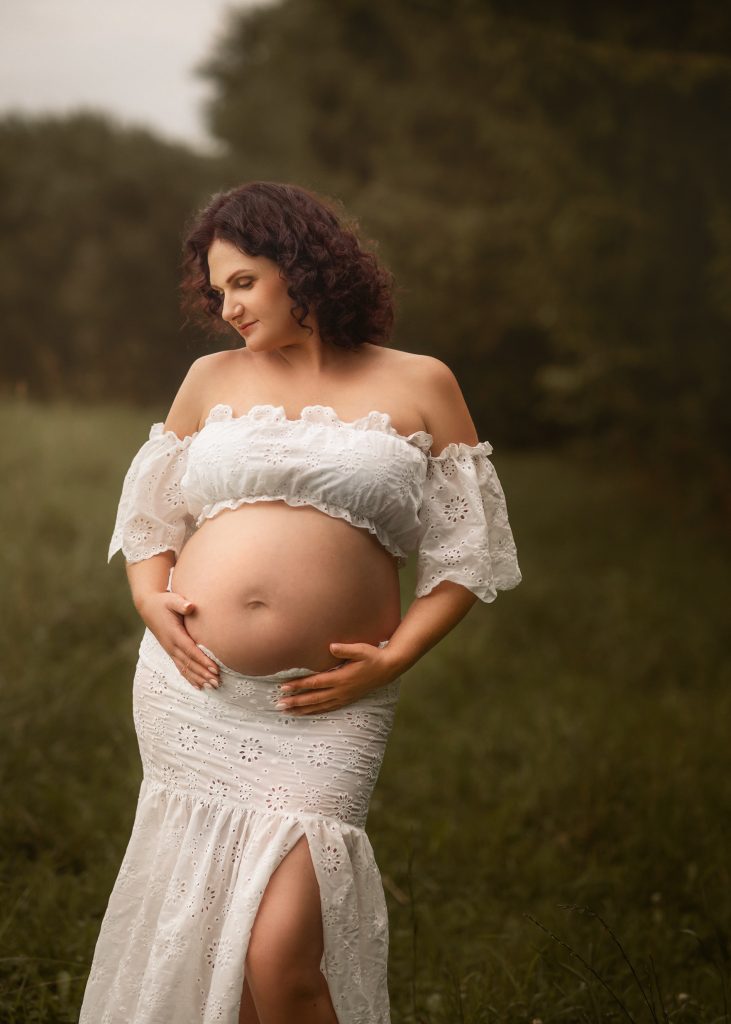 natural maternity photo taken outdoors in nature wearing white outfit guided posing Surrey South London photoshoot