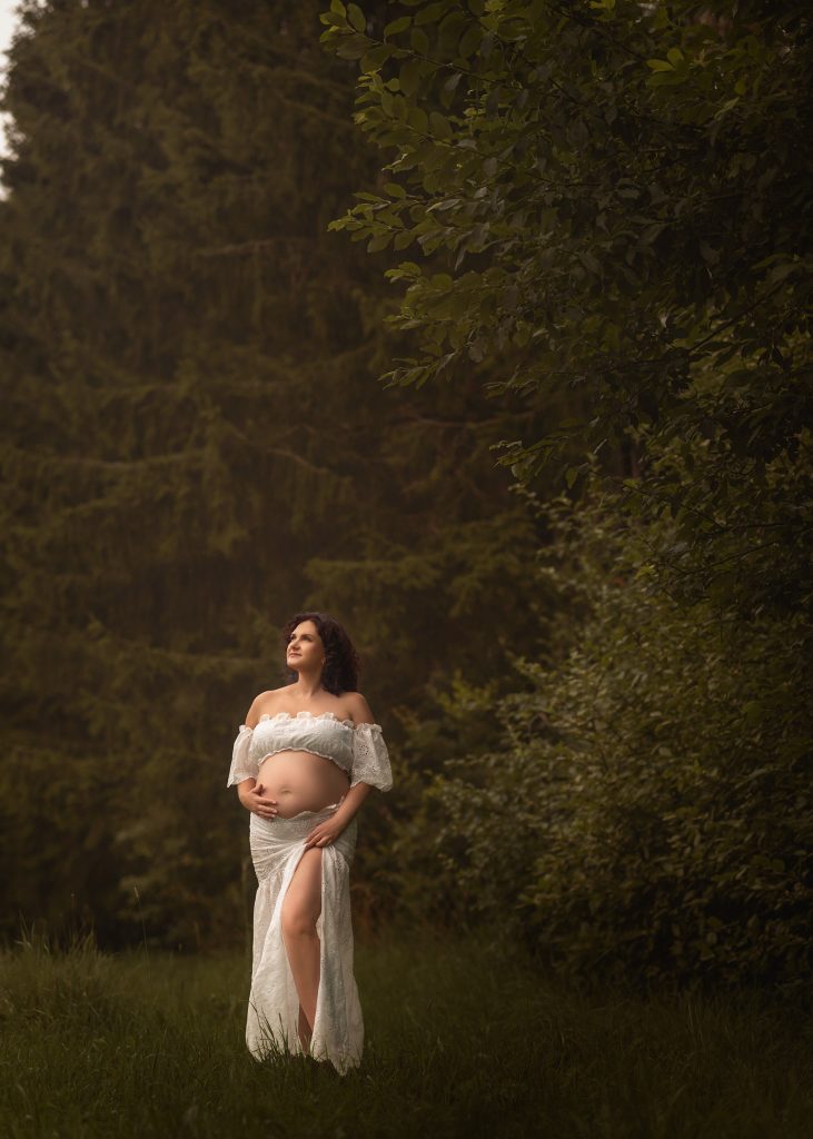 expectant mother standing in the white outfit beneath the trees Surrey photoshoot